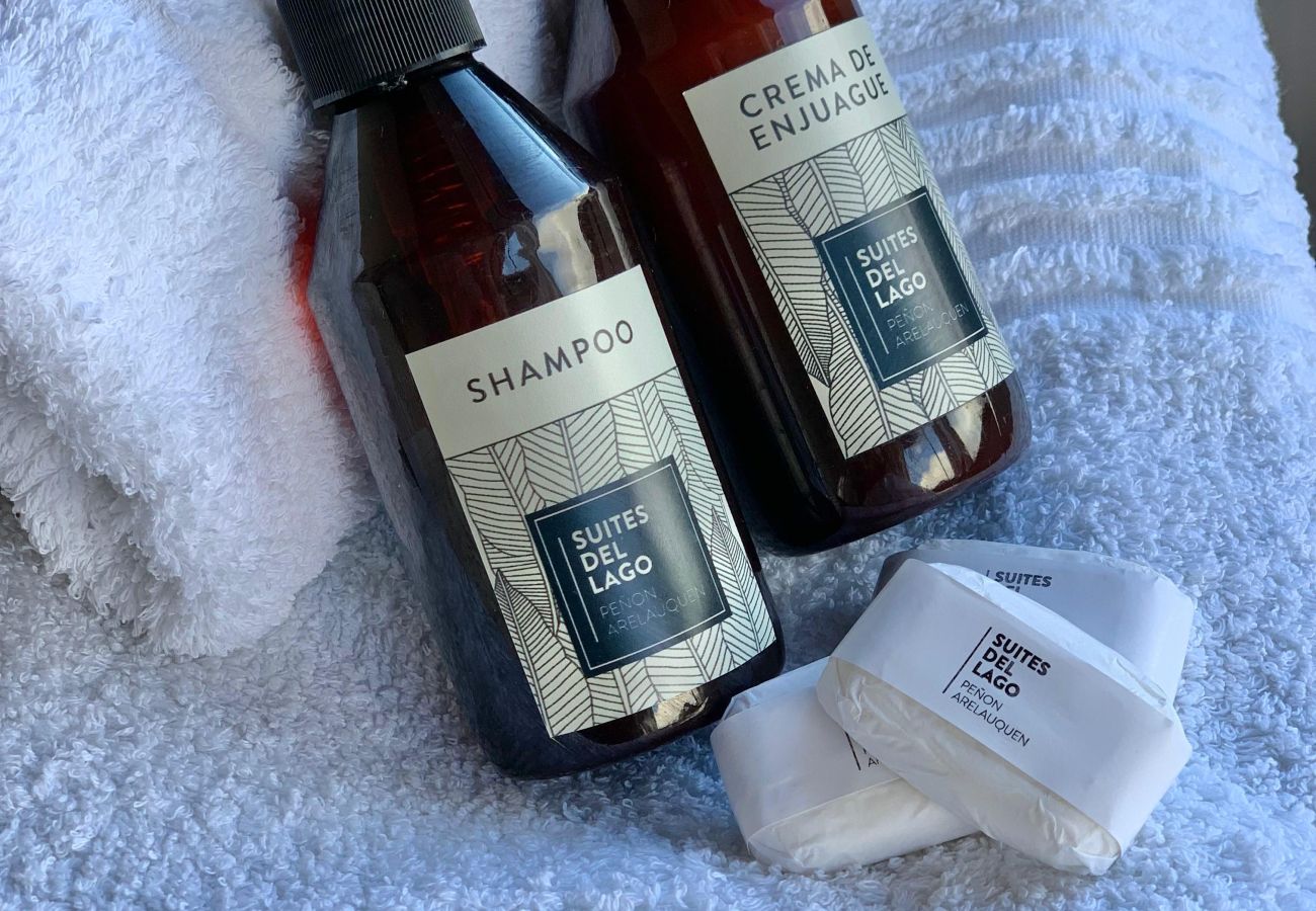 Detalle de los amenities de cortesía del departamento Lenga 1D con champú, crema de enjuague y jabón de tocador.