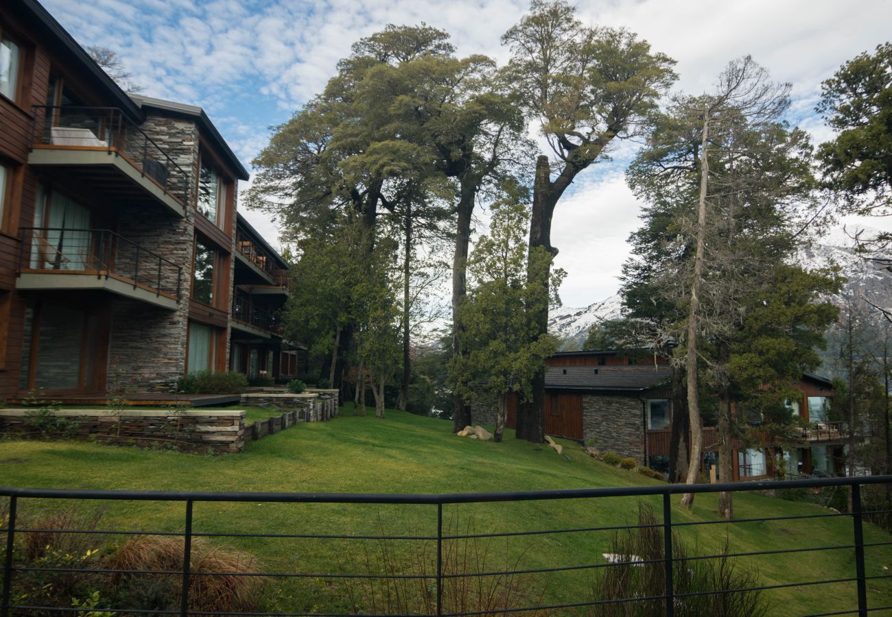 Jardín compartido de Suites del Lago, espacio verde rodeado de naturaleza para disfrutar al aire libre en Bariloche.