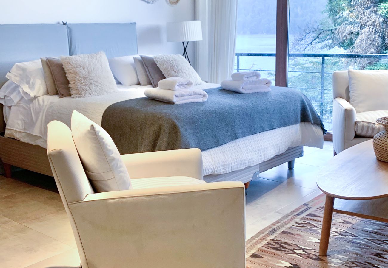 Estudio doble en Suites del Lago, con cama, sector de estar integrado, grandes ventanales y vistas a la naturaleza.