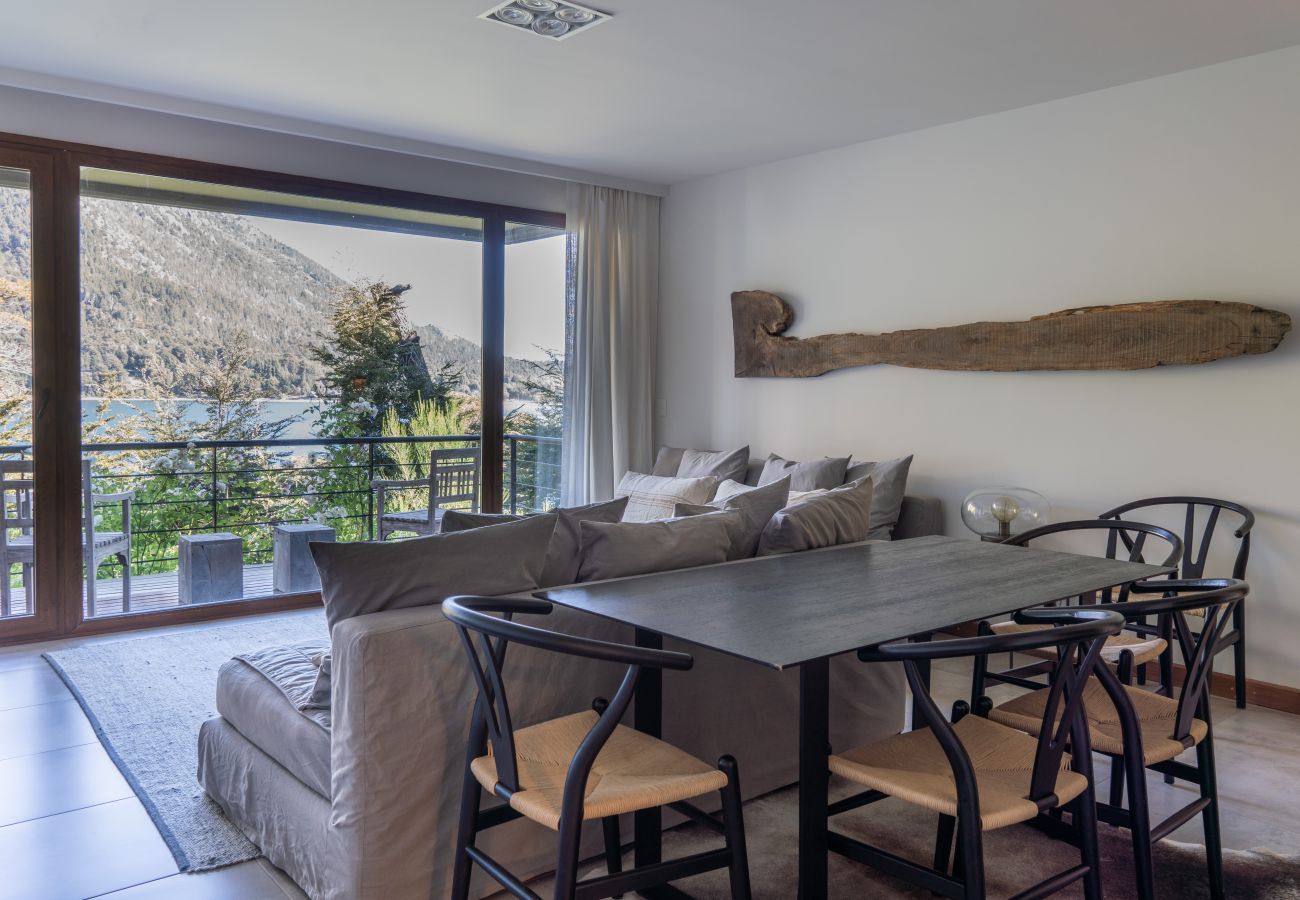 Living and dining area in Arrayán 1A apartment with dining table, seating area, and panoramic lake views.